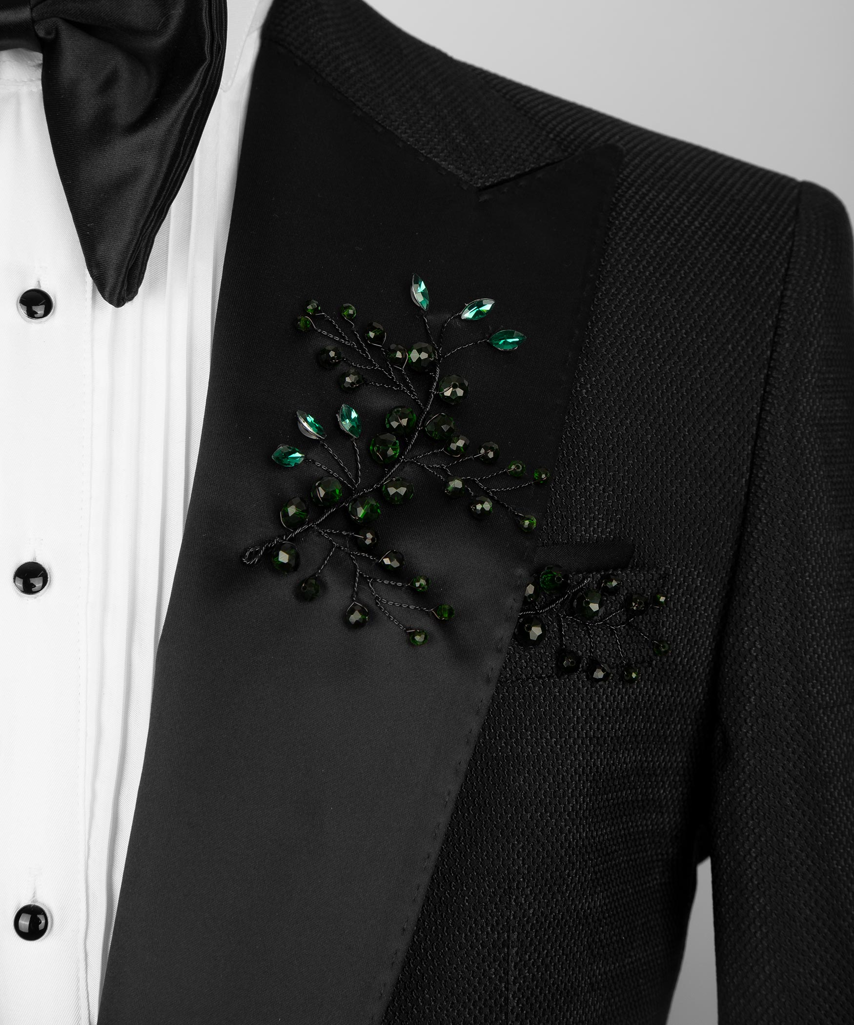 Close-up of black tuxedo breast pocket with green crystal floral embellishment