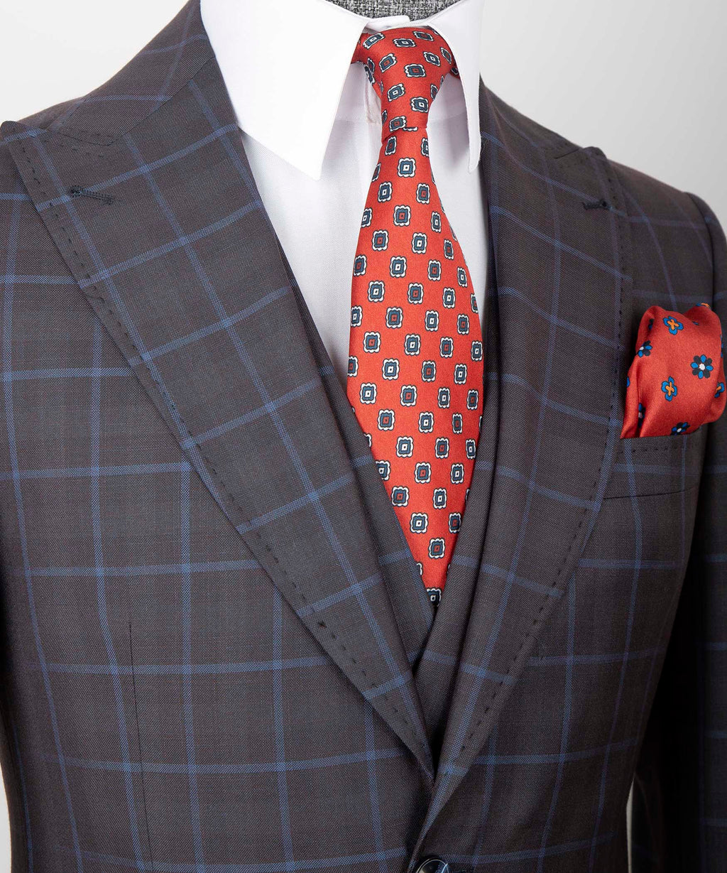 Close-up dark plaid vest jacket with red patterned tie and red pocket square