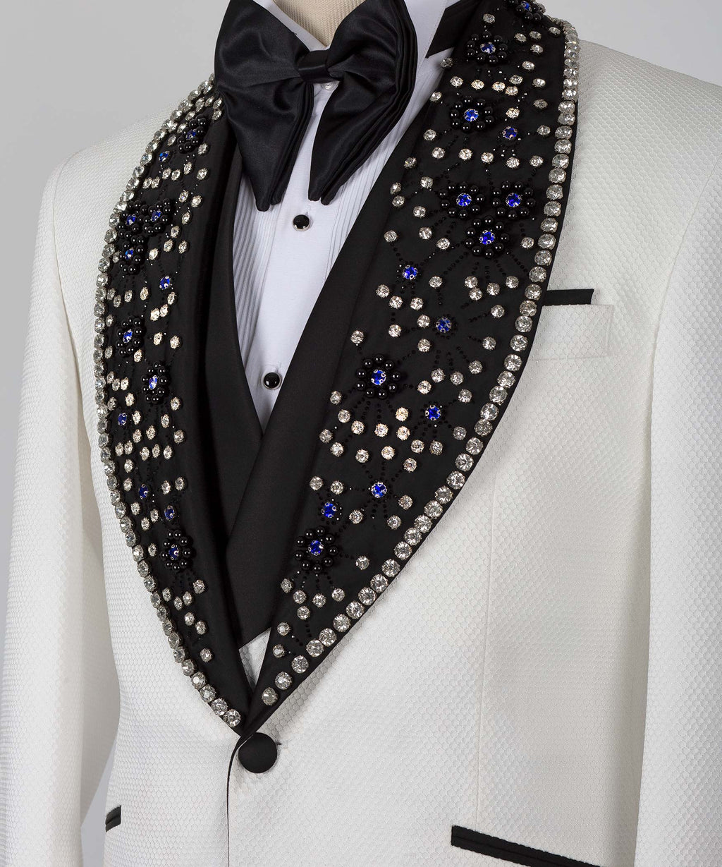 Close-up: white tuxedo jacket with black jeweled lapel, bow tie, and satin shirt front