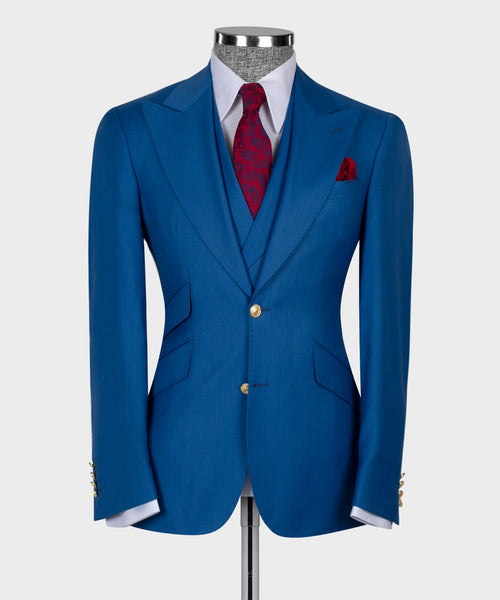Blue tailored suit jacket with gold buttons and red pocket square over white shirt