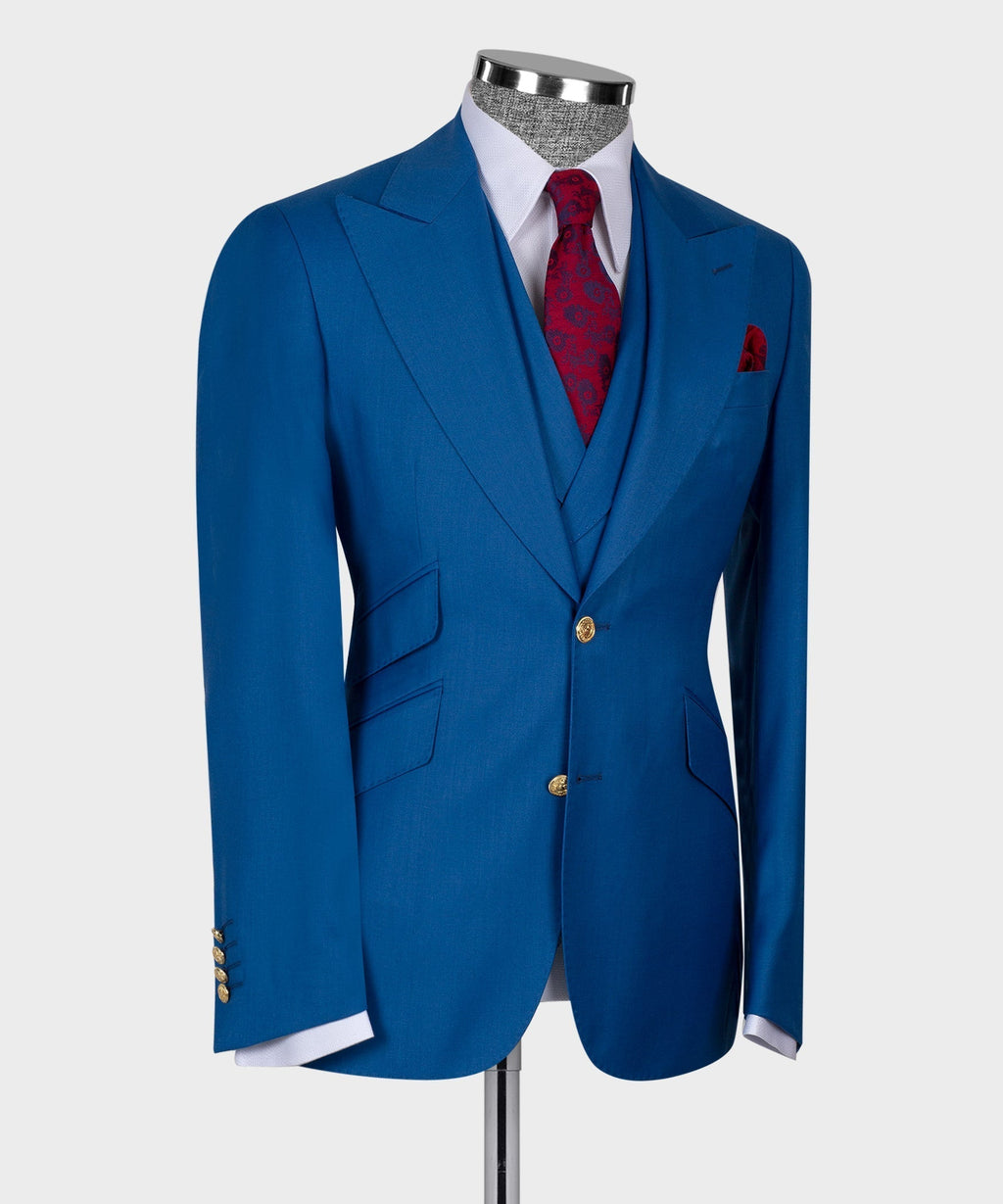 Blue three-piece suit with gold buttons, red patterned necktie, and welt pocket