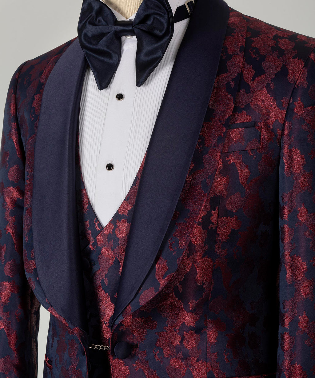 Tuxedo bow tie and dark lapels over burgundy patterned vest, satin sheen
