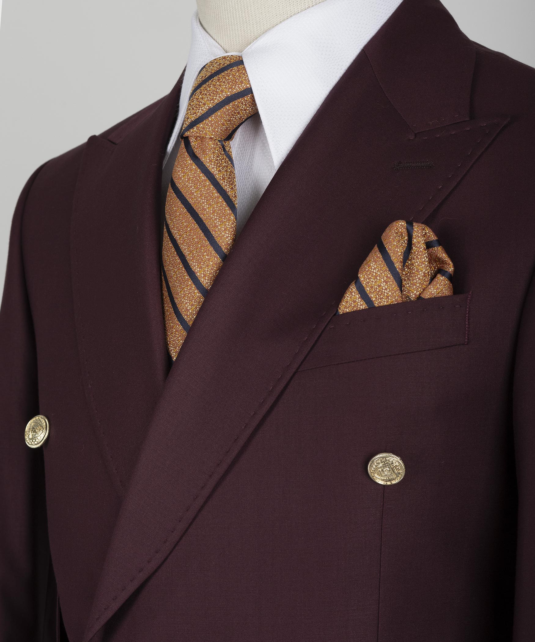Burgundy blazer lapels with striped gold-accent tie and matching pocket square