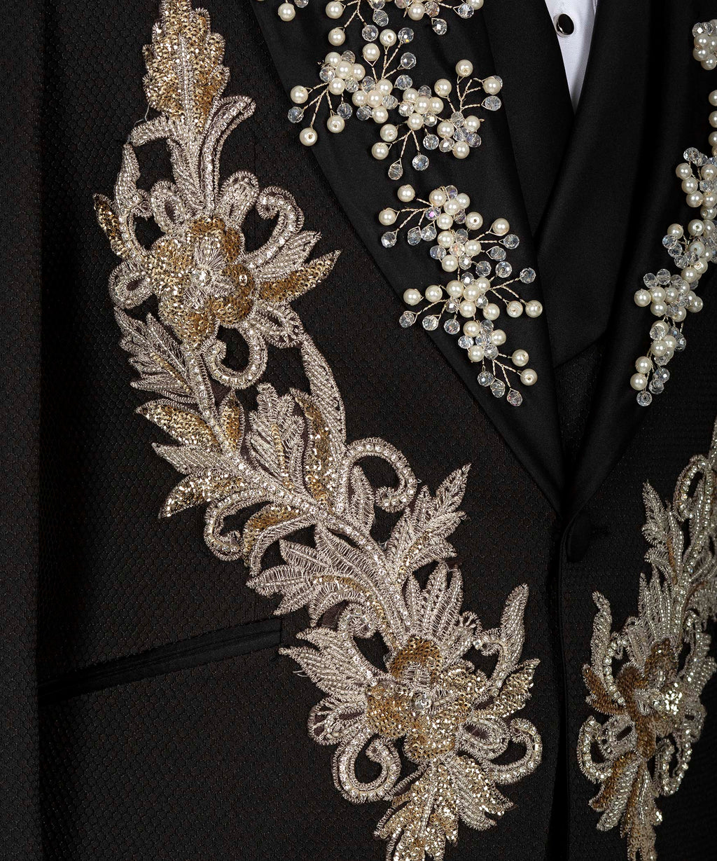 Close-up of black tuxedo jacket front with gold floral embroidery and pearl accents
