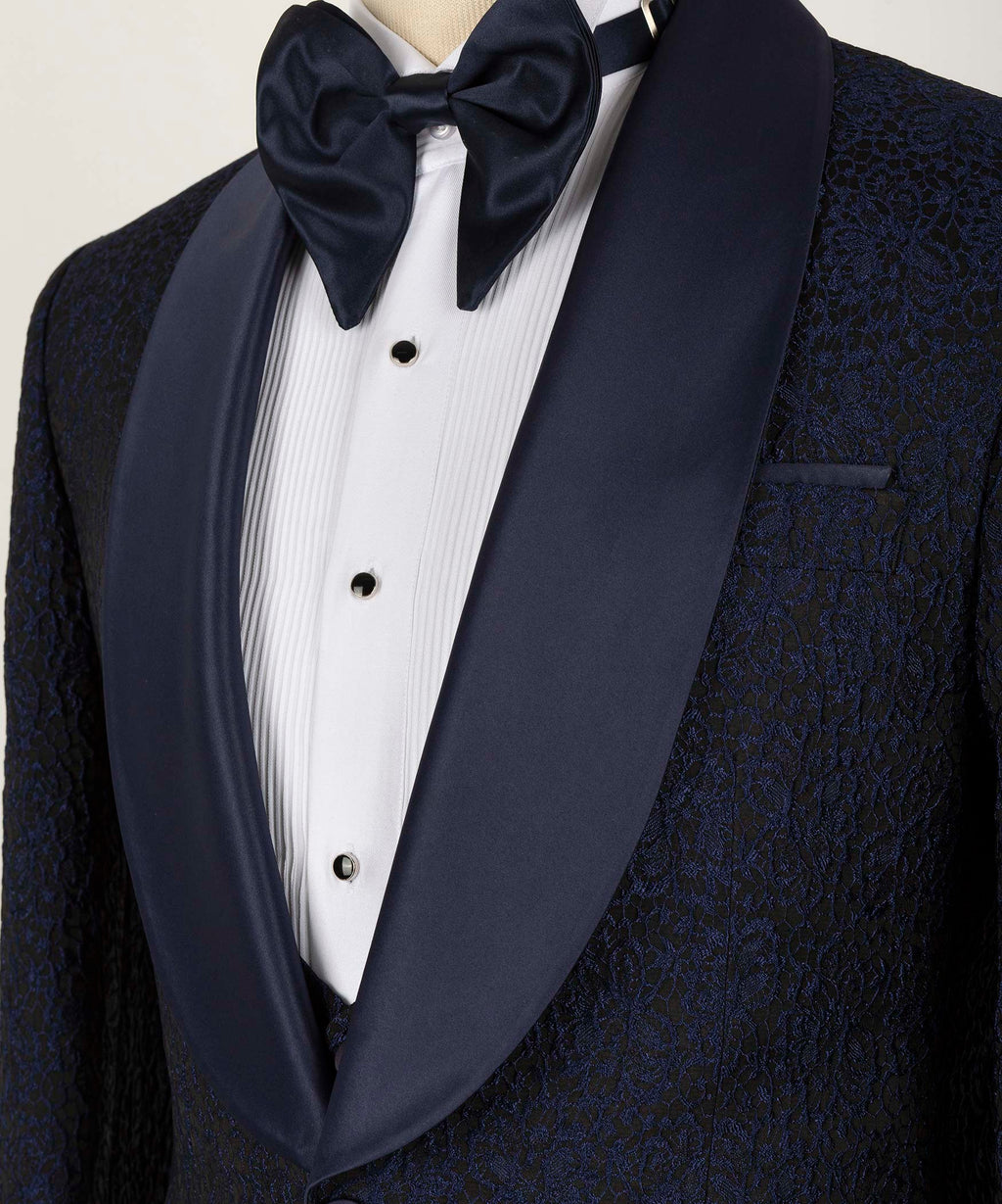 Close-up of bow tie and satin-trimmed lapels over white tuxedo shirt and vest.