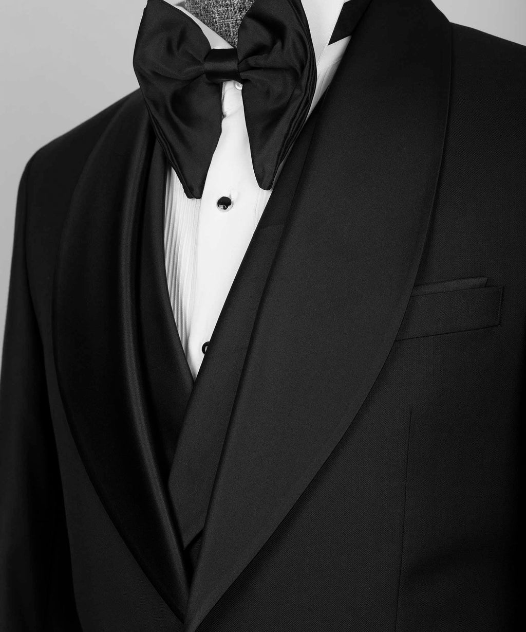 Close-up of black satin bow tie, white shirt, and tuxedo lapels with pocket square