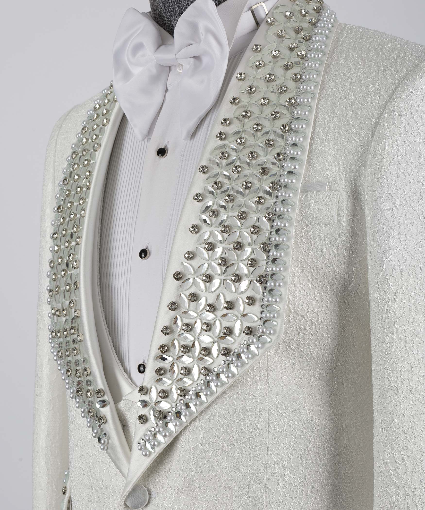 Close-up: white tuxedo jacket with bow tie and crystal studded lapel detail