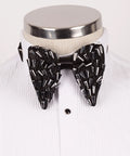 Koss Atelier black silk bow tie adorned with metallic silver spikes, displayed on a white tuxedo shirt.
