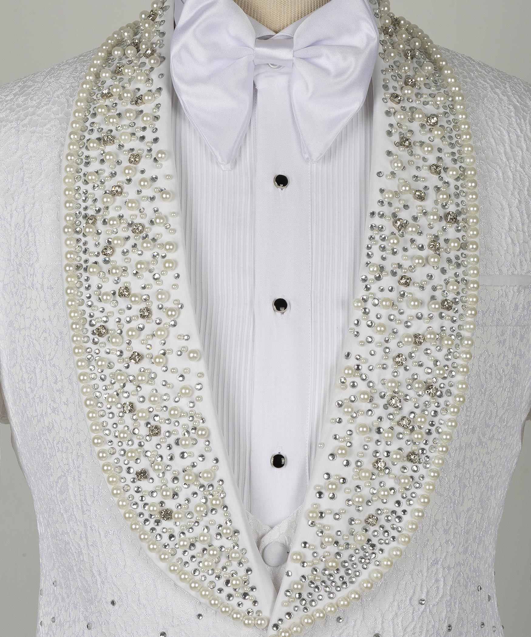 Close-up white tuxedo shirt front with bow tie and gold gem-studded lapels