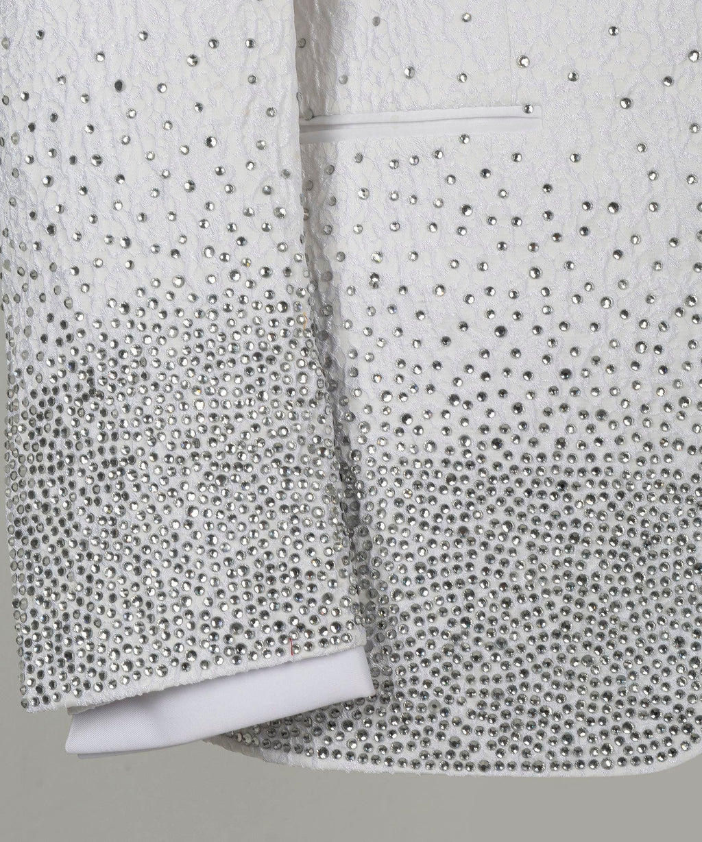 Close-up white tuxedo sleeves with dotted rhinestone-like embellishment at cuffs