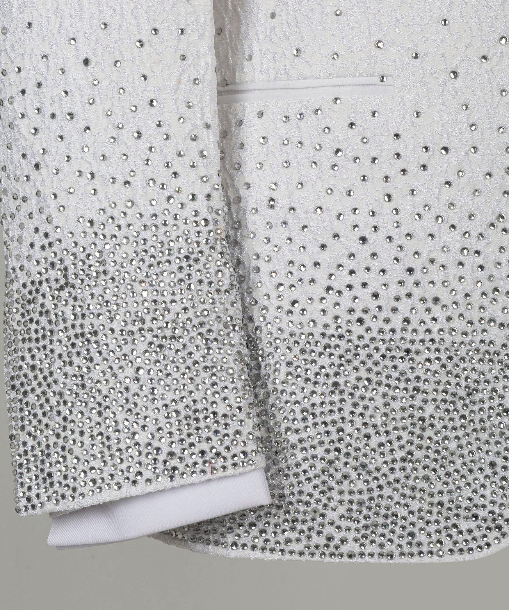 Close-up white tuxedo sleeves with dotted rhinestone-like embellishment at cuffs