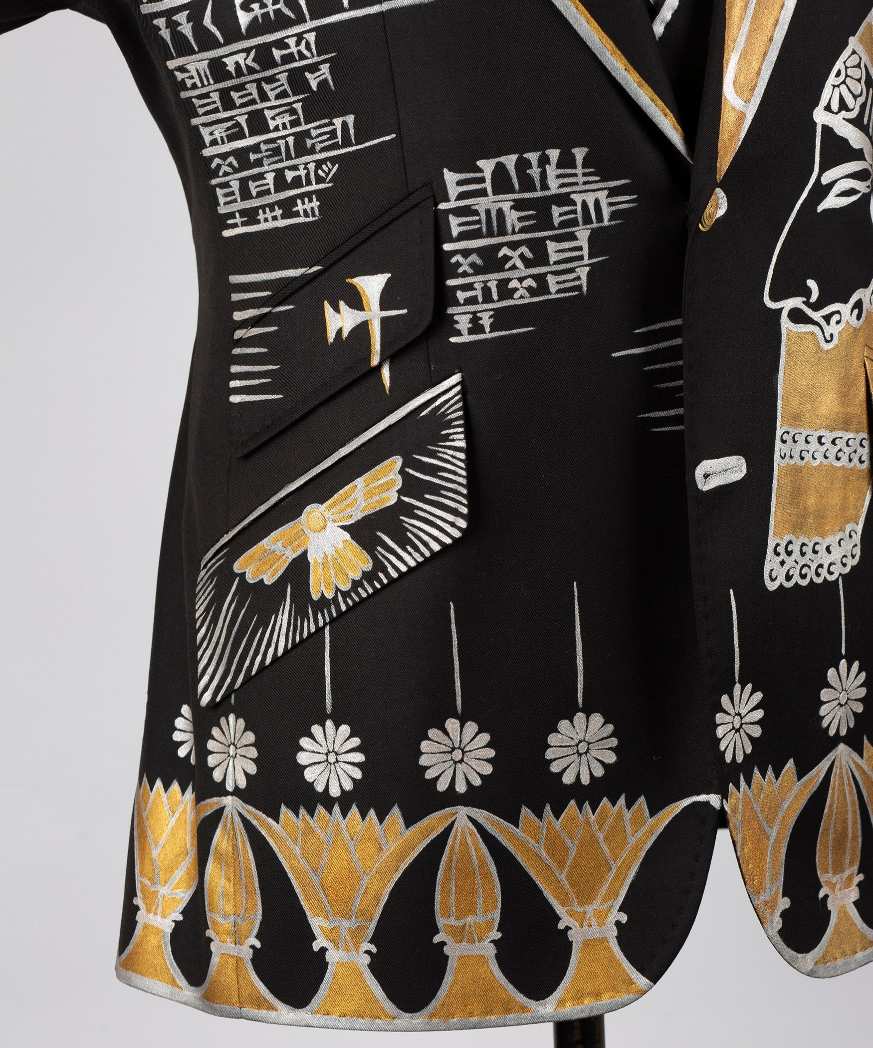 Black tuxedo jacket hem close-up with gold-and-white embroidery and scalloped bottom