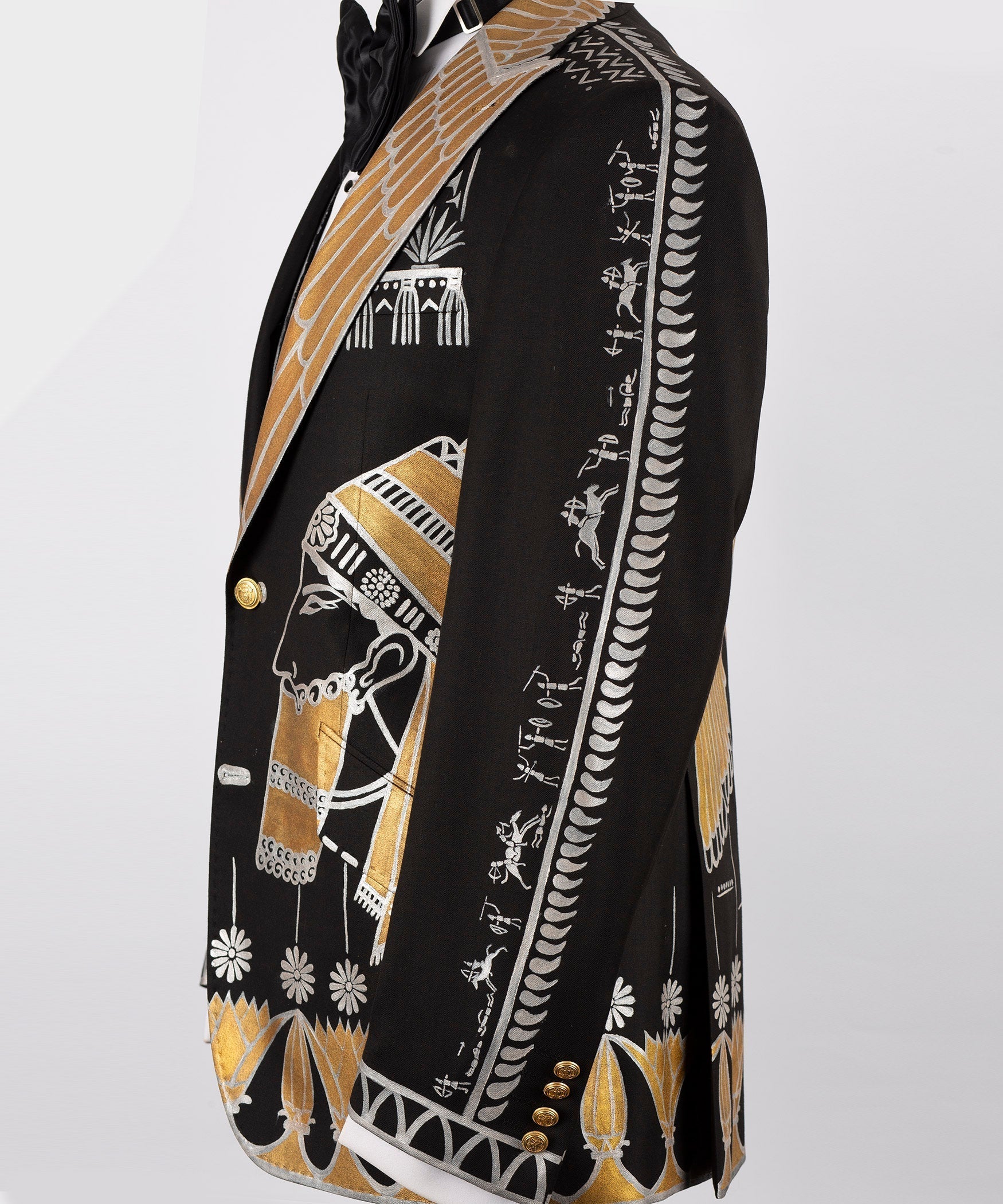 Black tuxedo jacket side view with gold-and-white embroidered panel and gold button