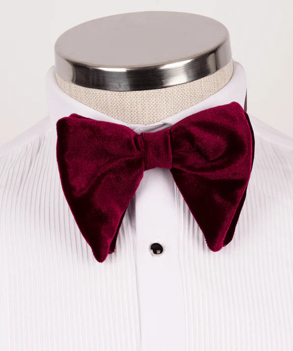 Koss Atelier deep burgundy velvet bow tie on a crisp white tuxedo shirt. Sharp, pointed-end formal accessory.