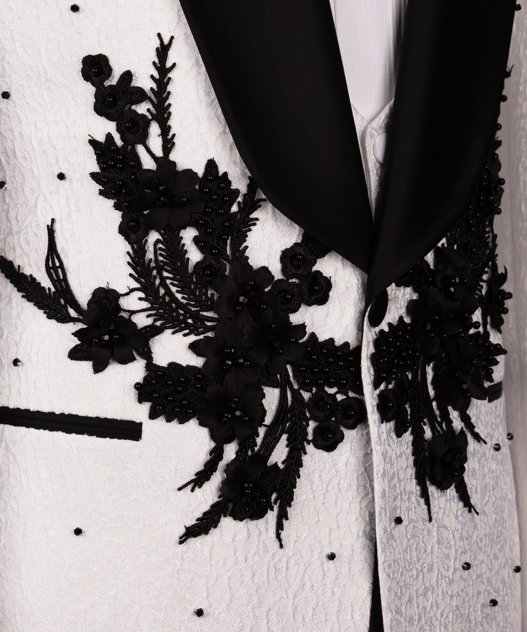 Close-up of black floral appliqué on white tuxedo jacket lapel