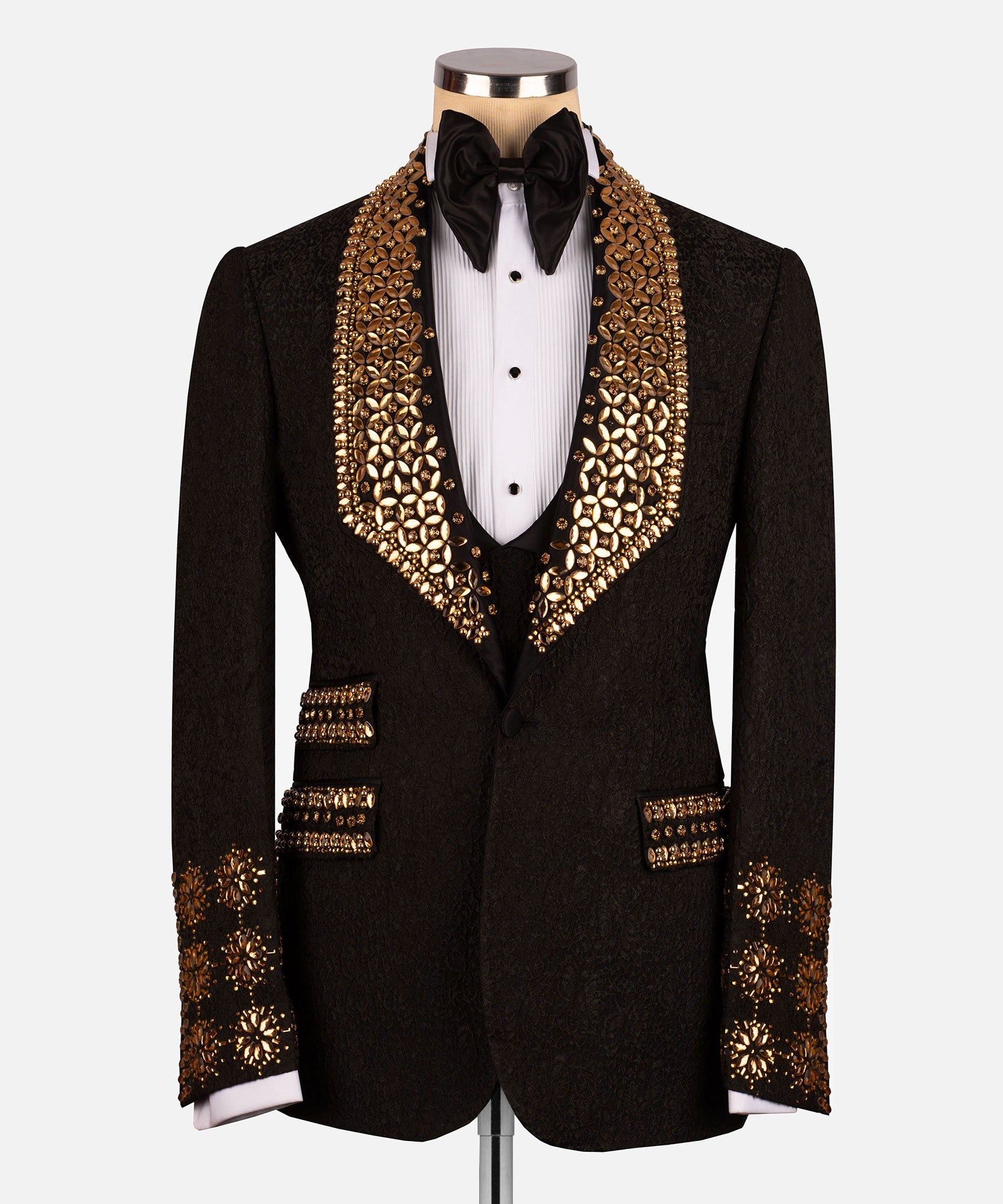 Black tuxedo jacket with gold gem-like trim on lapels, cuffs, and pockets; black bow tie