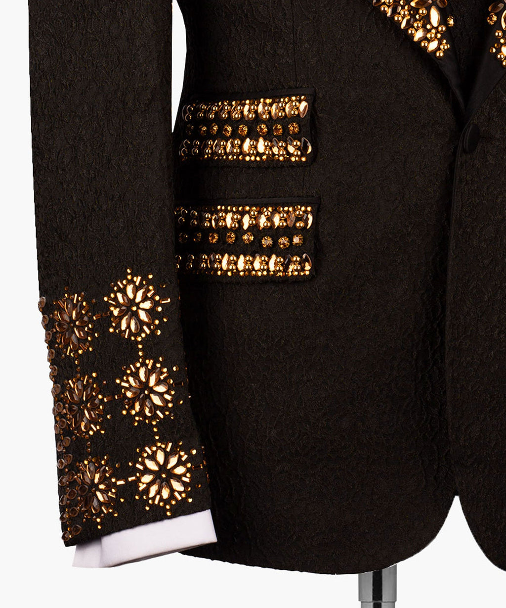 Gold beaded cuff and pocket trim on black tuxedo sleeve and chest; textured fabric