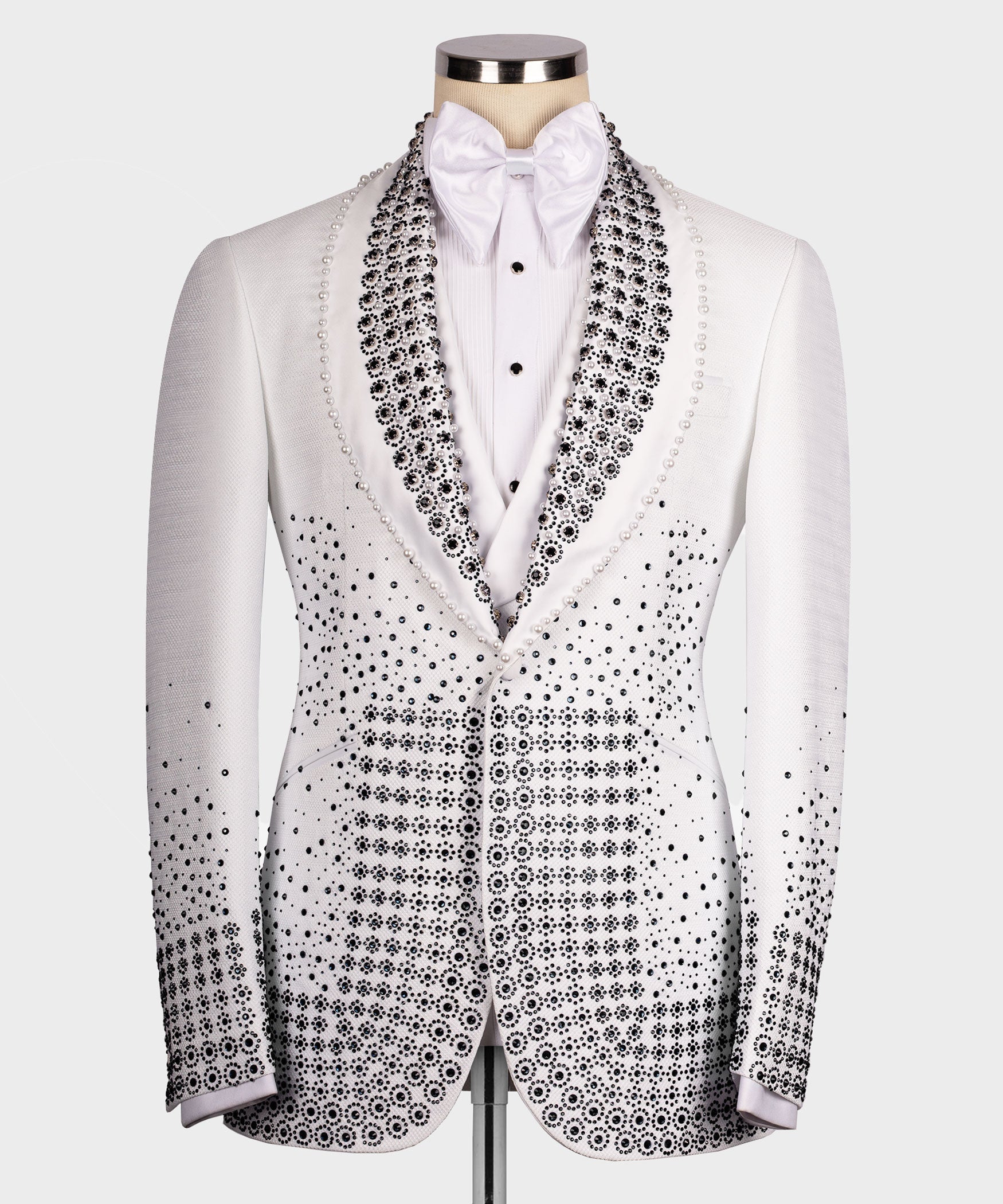 White tuxedo jacket with black gem-studded lapels, bow tie, and patterned front