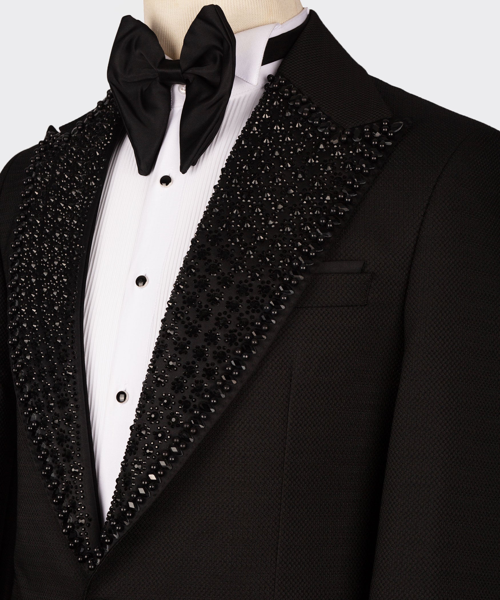Close-up: black bow tie, white dress shirt, jeweled shawl lapel on black tuxedo