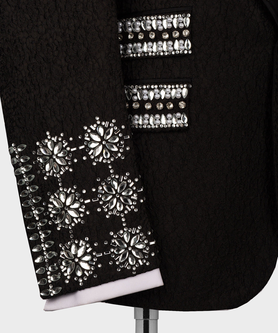 Close-up of black tuxedo sleeve and front panel with floral rhinestone and pearl details