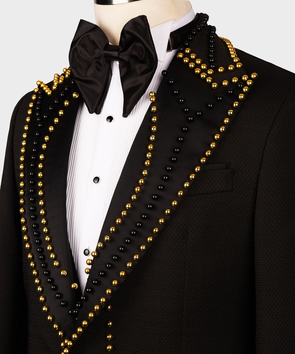 Close-up of black tuxedo lapels with gold pearl and bead rows, bow tie and pocket detail