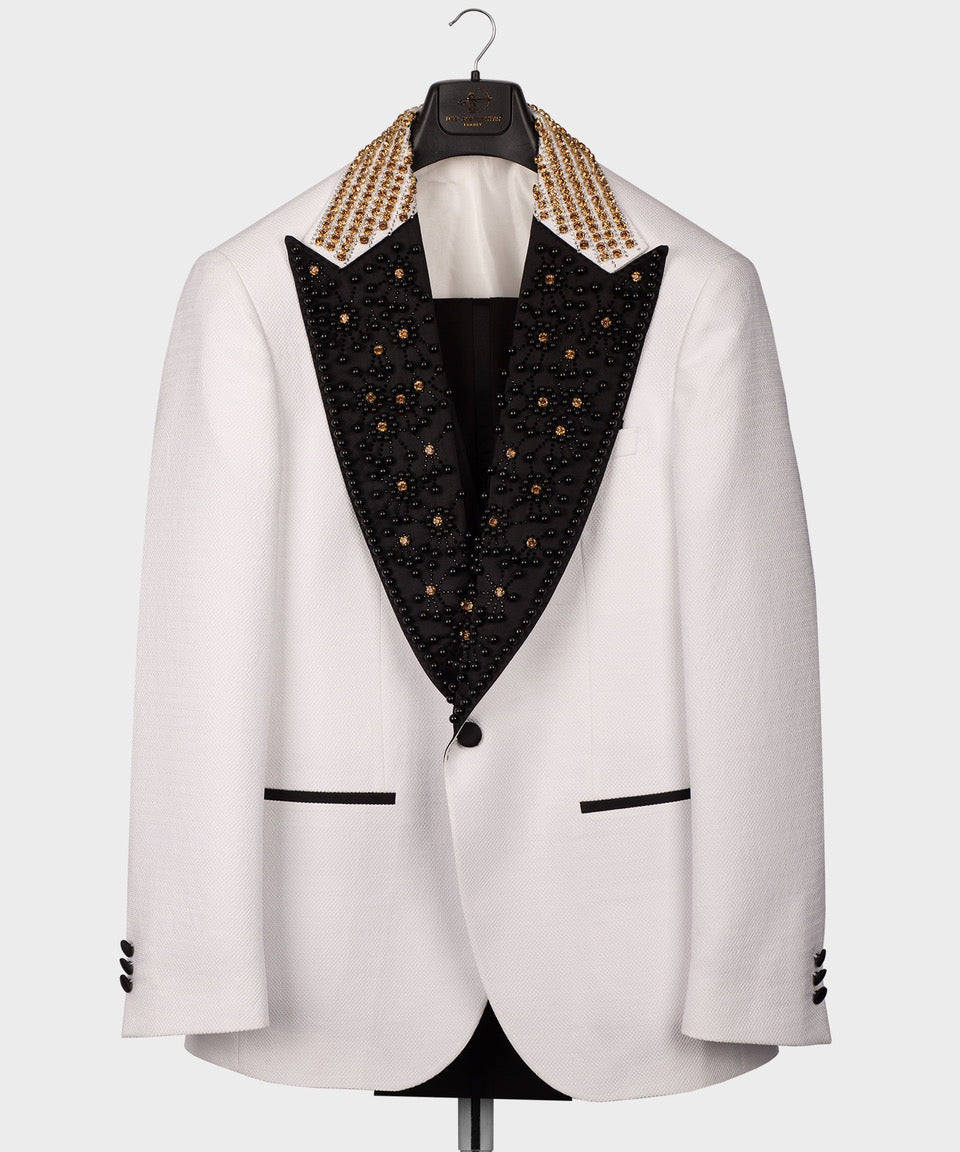White tuxedo jacket on hanger with black embellished lapels and gold chain trim