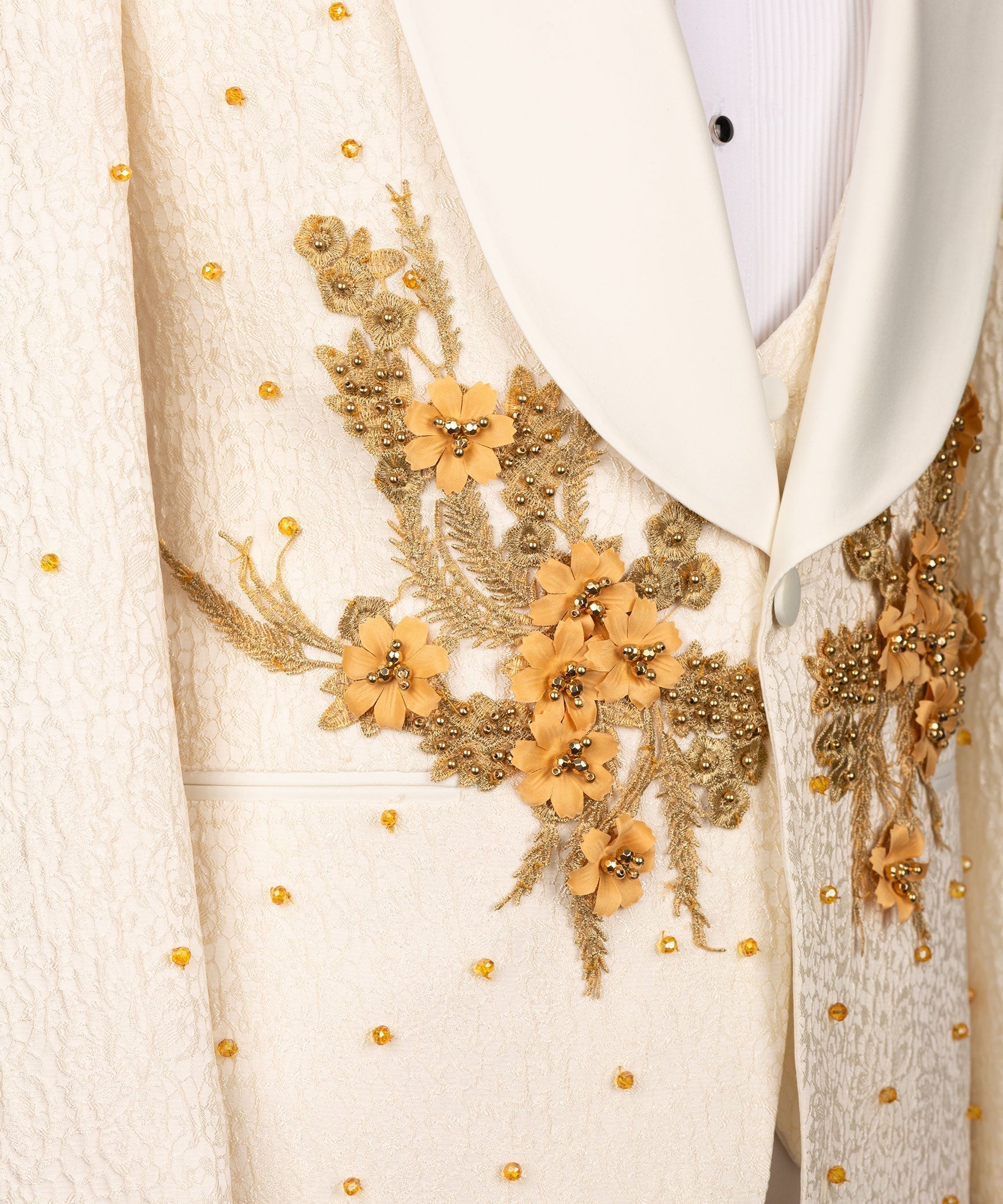 Close-up: cream tuxedo jacket with gold floral appliqué and bead-like accents
