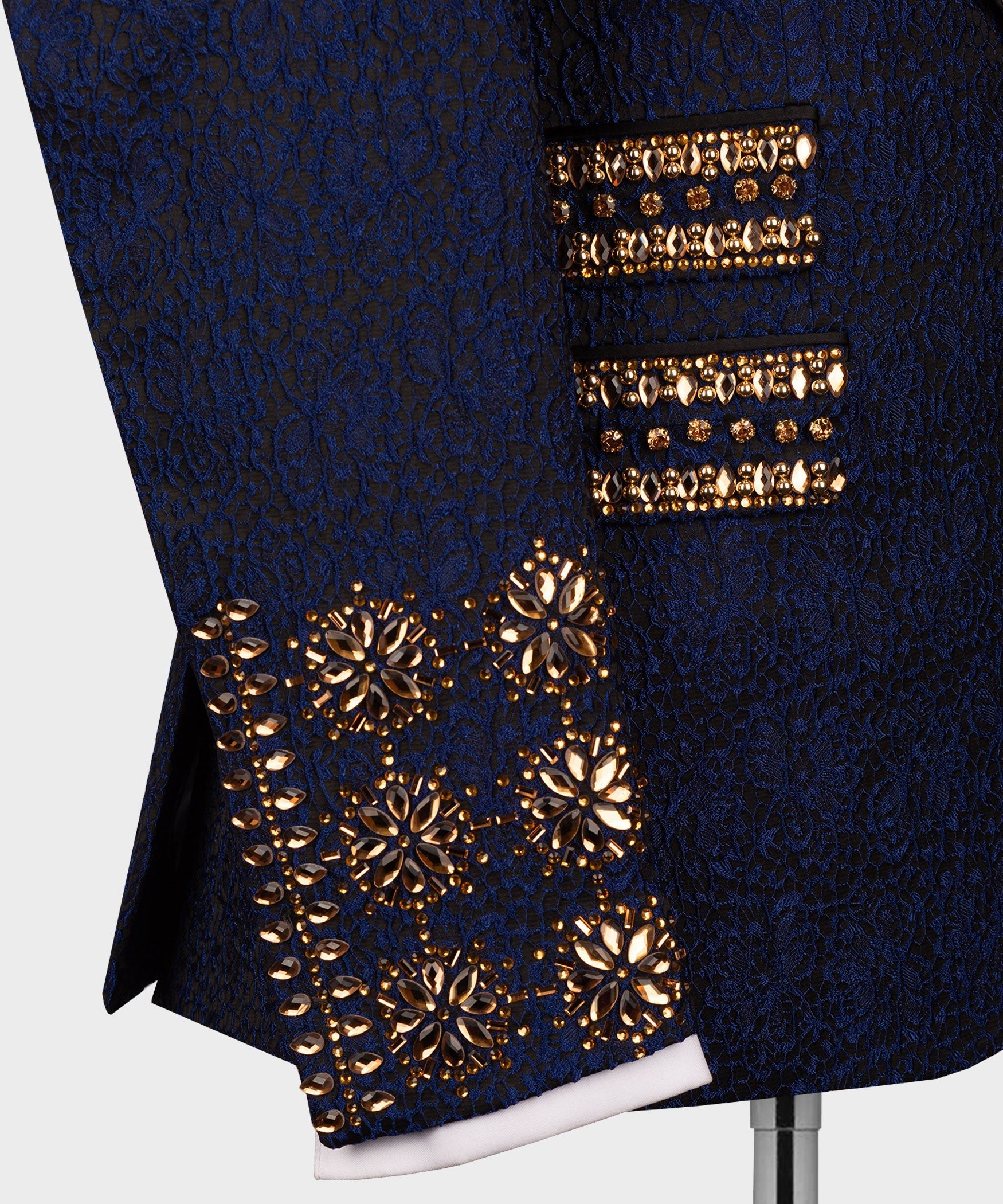 Navy tuxedo close-up showing gold floral beadwork on pocket flap and lower hem
