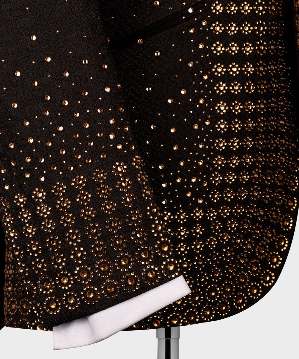 Close-up of black tuxedo fabric covered with gold gem-like dots and circle patterns
