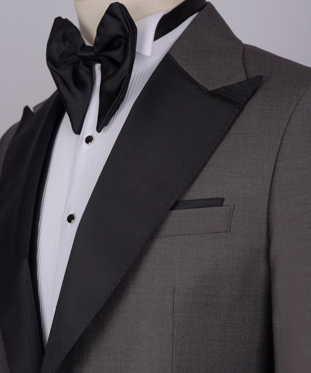 Black bow tie, white striped shirt, and charcoal tuxedo jacket lapel with pocket detail