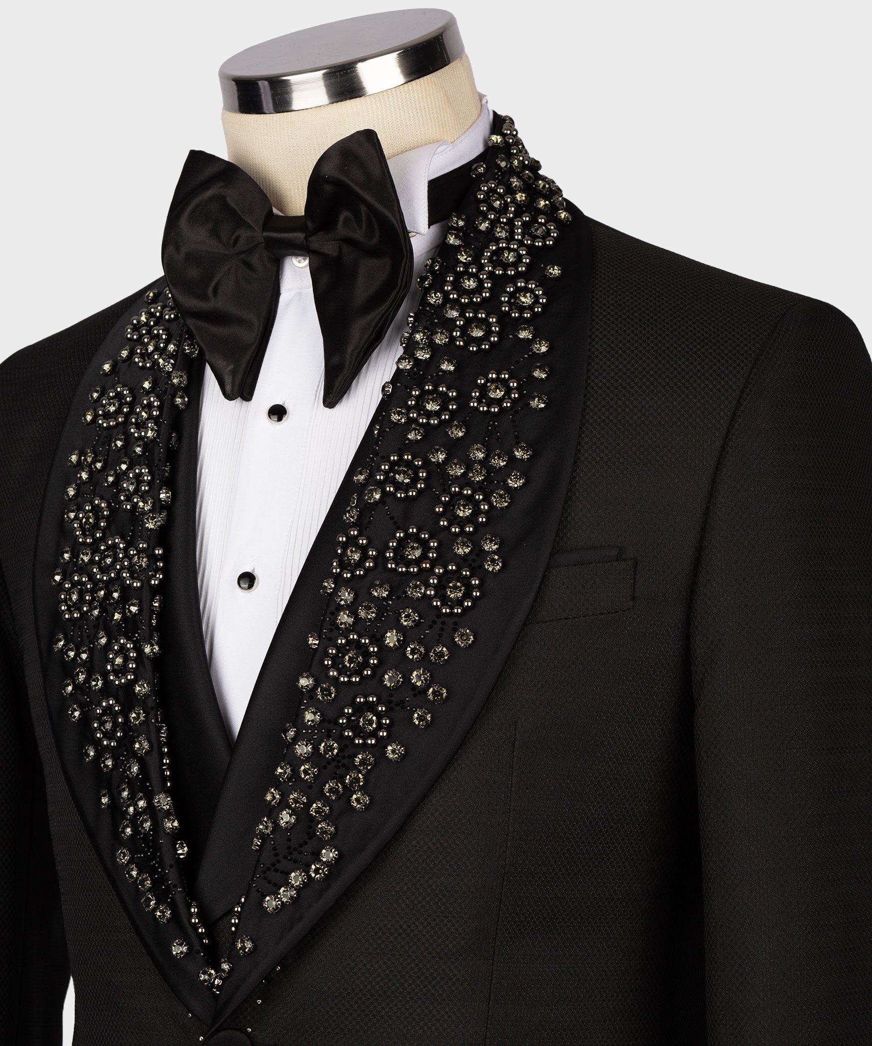 Close-up of black tuxedo lapels with gold-toned gem embellishments and satin bow tie