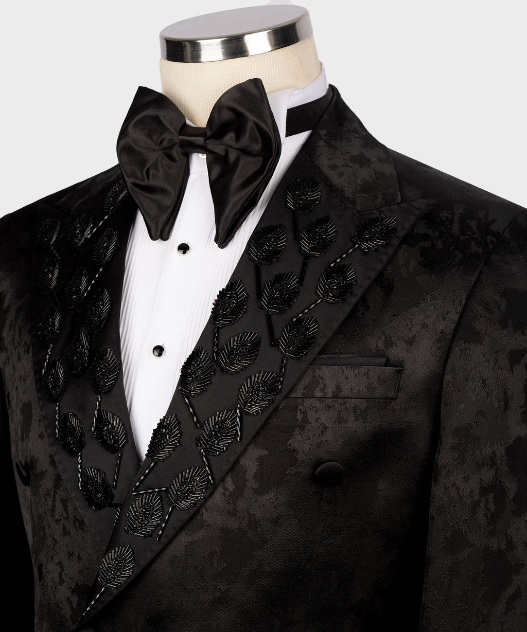 Close-up: black tuxedo lapel with ornate pattern and satin bow tie