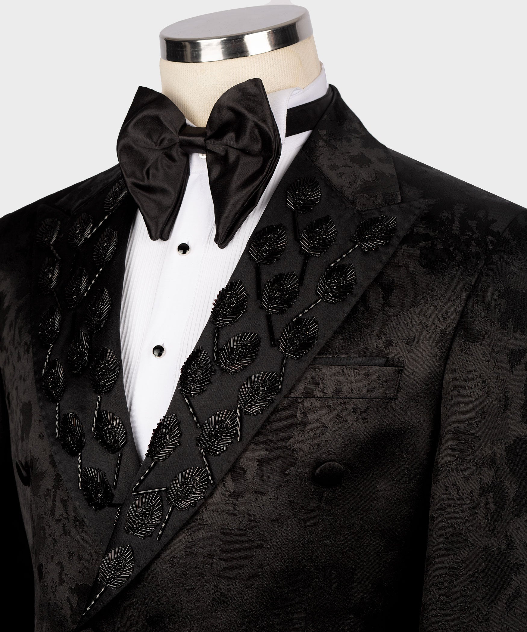 Close-up: black tuxedo lapel with ornate pattern and satin bow tie