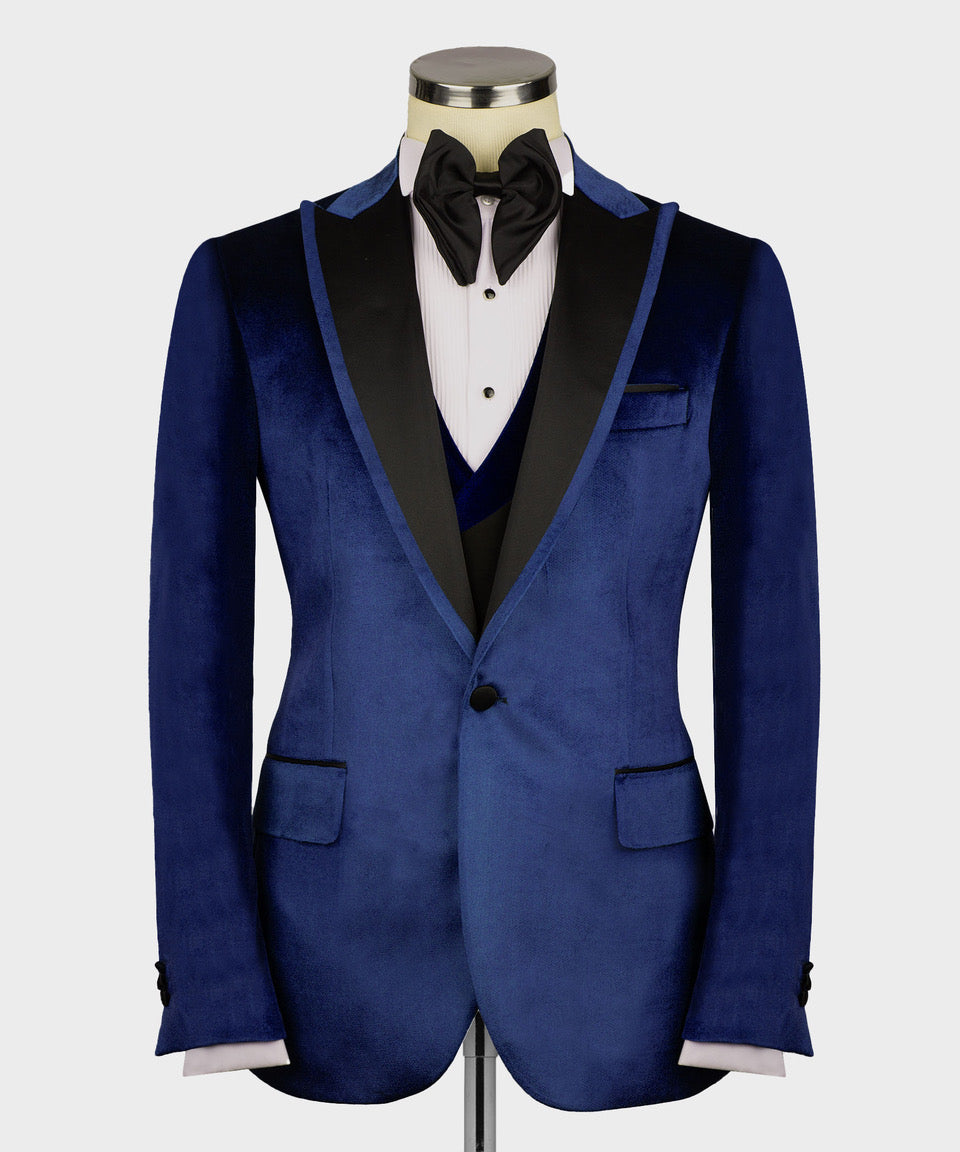 Blue velvet tuxedo jacket front with notch lapels, chest pocket, black bow tie and vest
