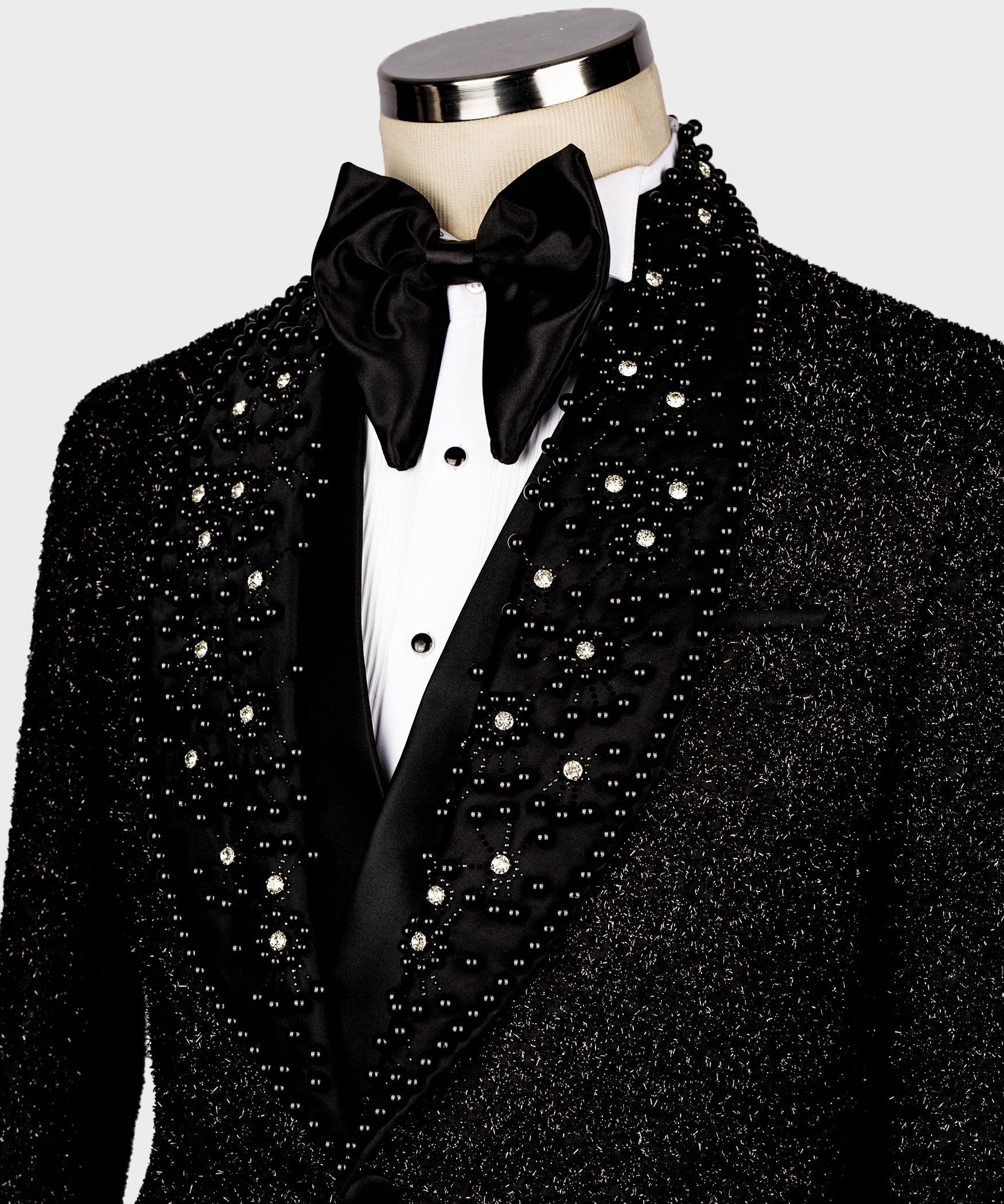 Close-up of black glitter tuxedo jacket lapels with rhinestone accents and bow tie
