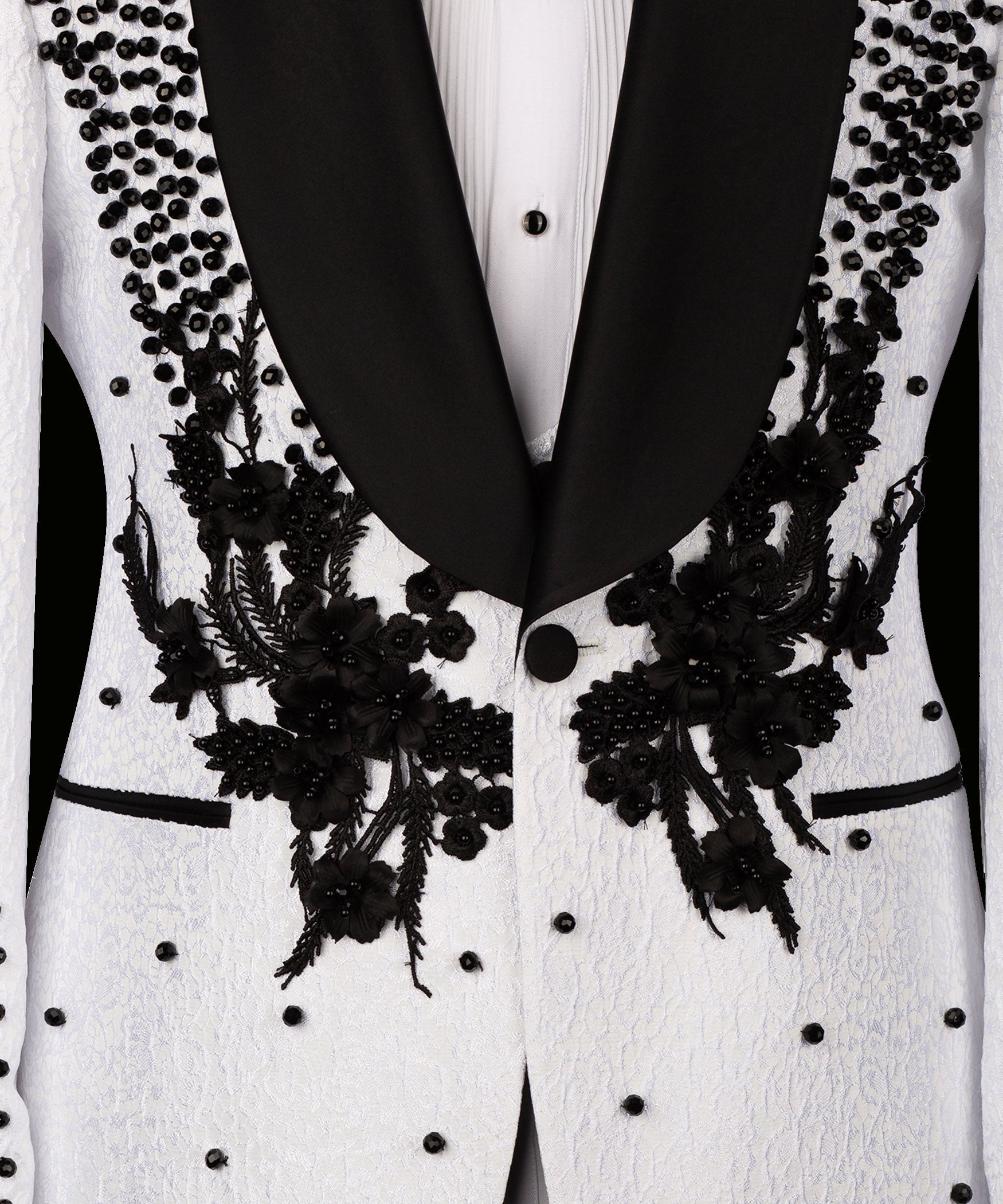 Close-up: white tuxedo jacket front with black floral appliqué and studded details