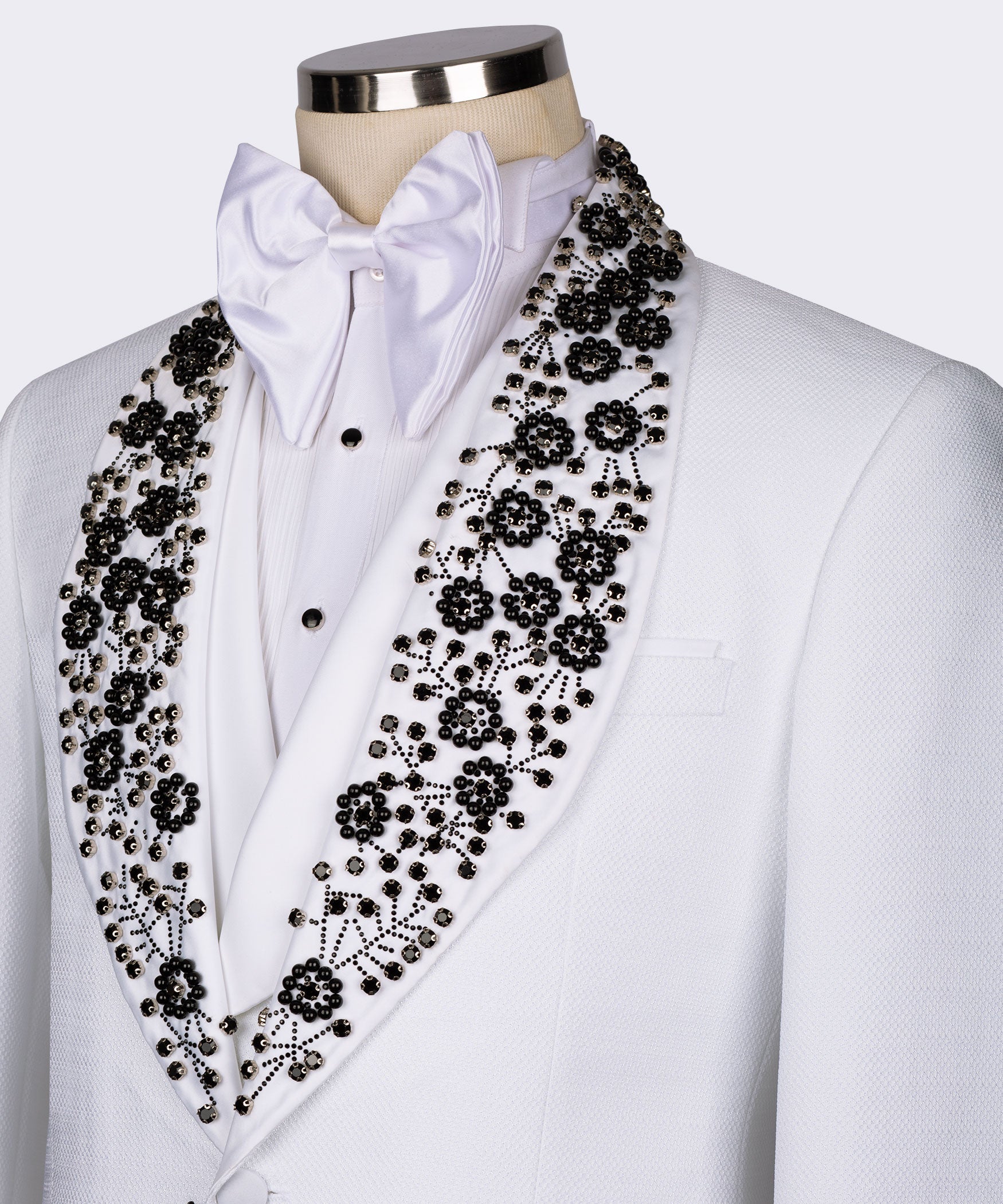 Close-up: white tuxedo lapel with black gemstone floral embroidery and satin bow