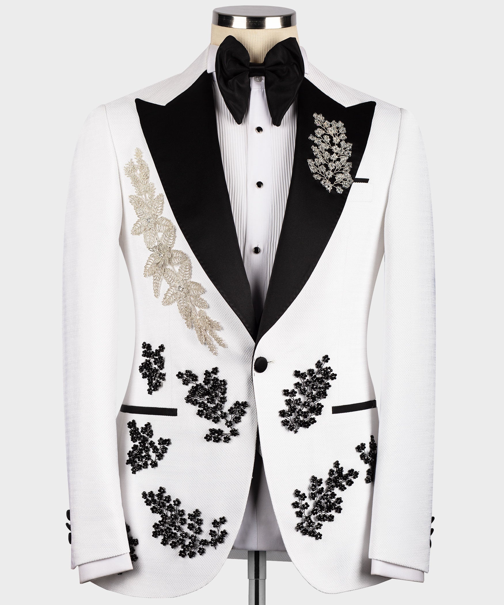 White tuxedo jacket with black lapels, gold floral trim, and black bow tie