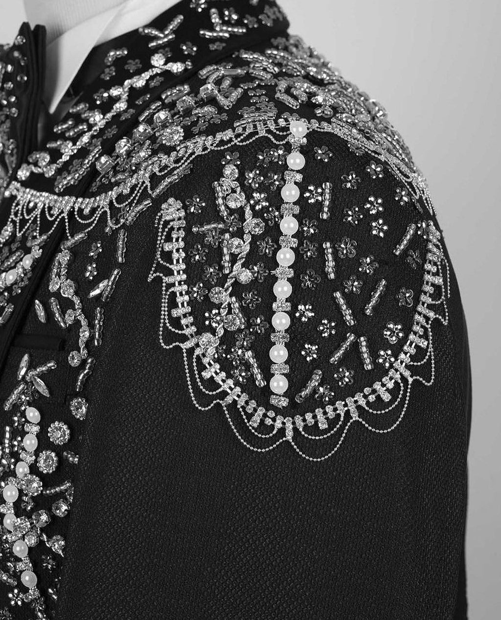 Black jacket shoulder with ornate silver bead chains and dangling pearl motifs