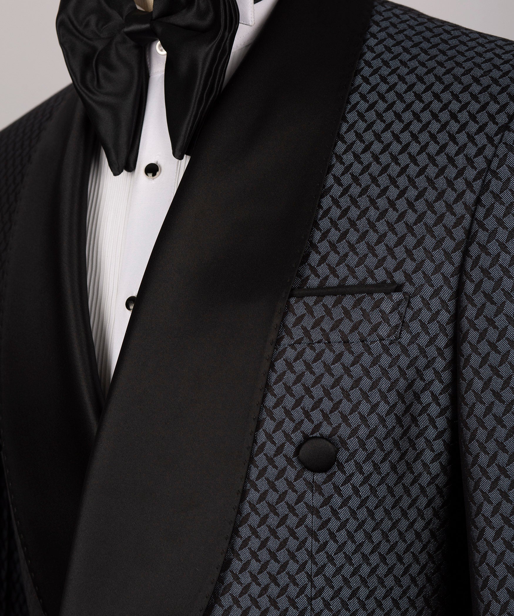 Close-up of satin black lapel, bow tie and patterned chest pocket on tuxedo jacket