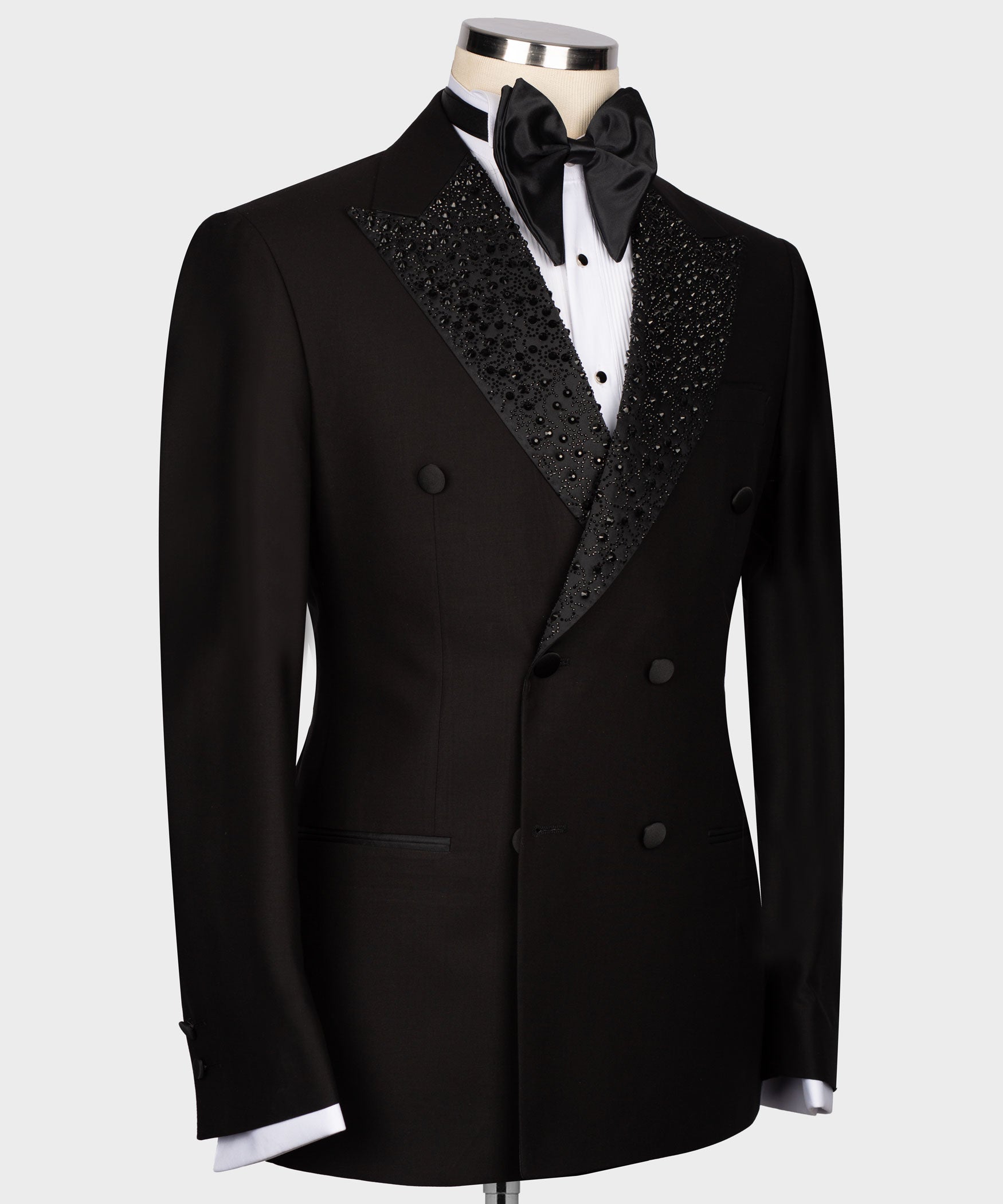 Black tuxedo jacket front view with jeweled lapel panel detail and satin bow at collar