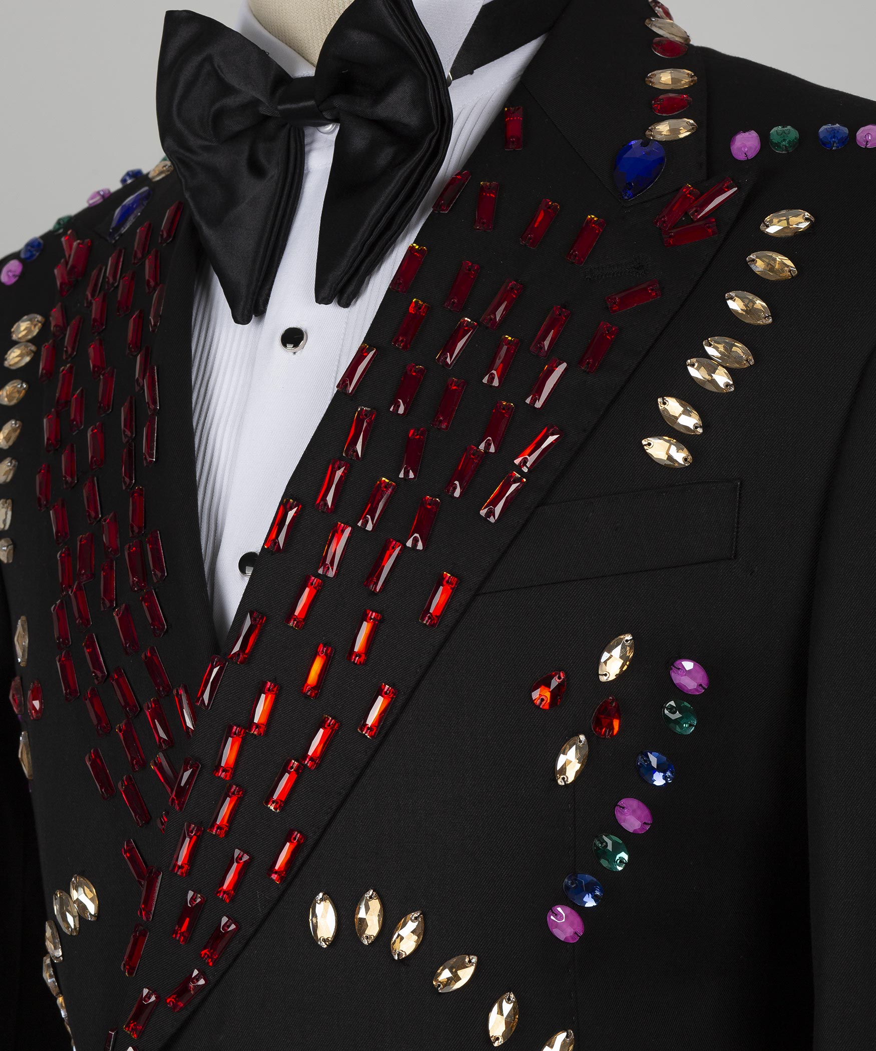 Close-up: black satin bow tie and crystal-studded lapel with red, gold and blue accents