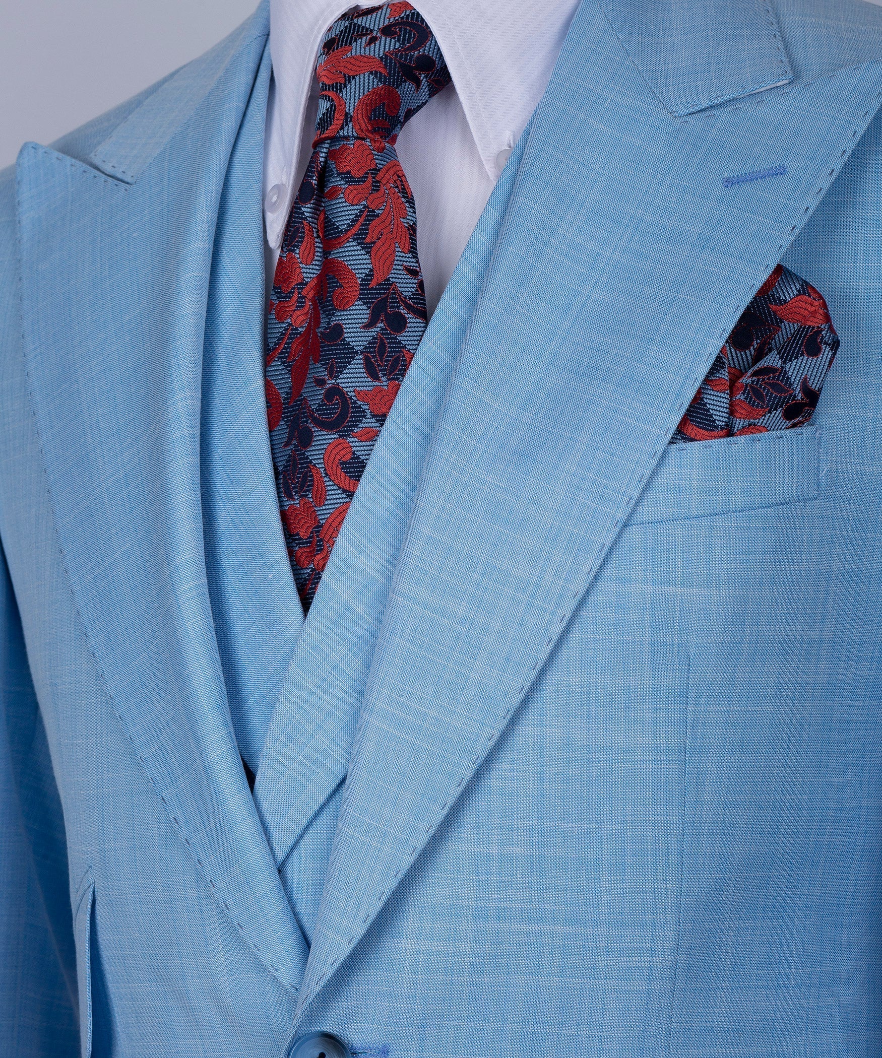 Light blue suit jacket with red patterned tie and coordinating red pocket square detail