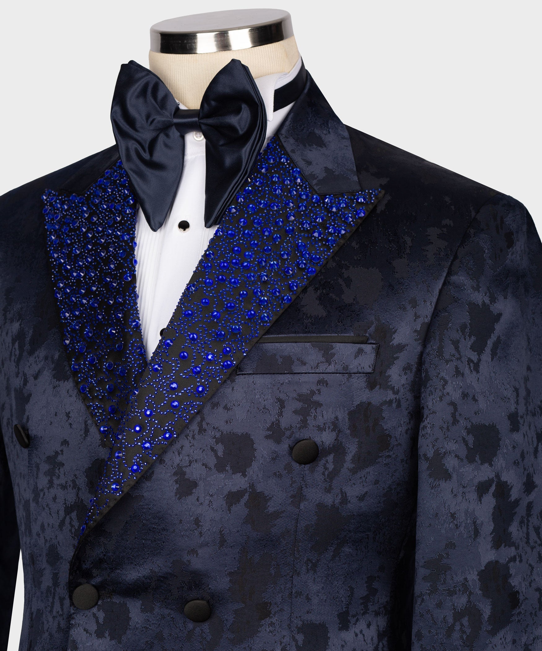 Close-up tuxedo shirtfront with navy bow tie and blue gemstone-embroidered lapels