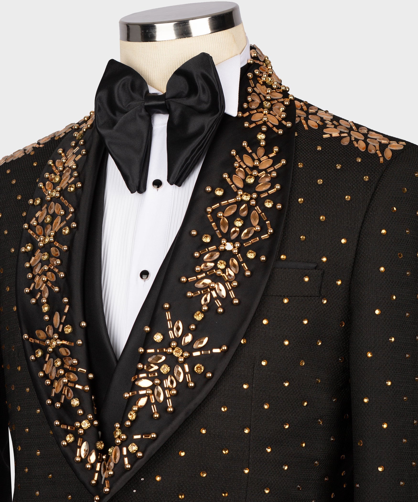 Black tuxedo jacket with gold embroidery, satin bow tie, and pleated white shirt