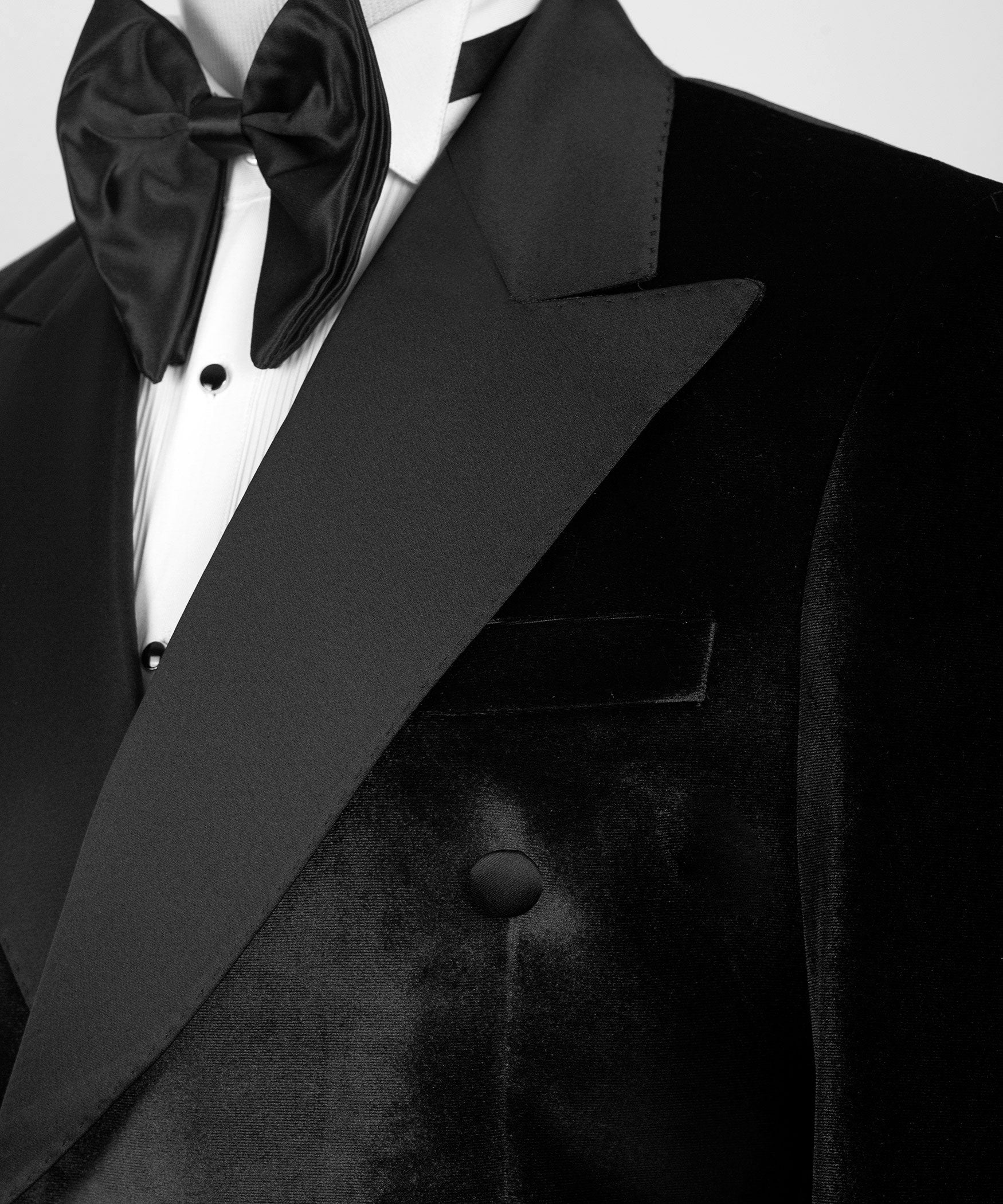 Close-up of black satin lapel, velvet jacket front buttons, and bow tie