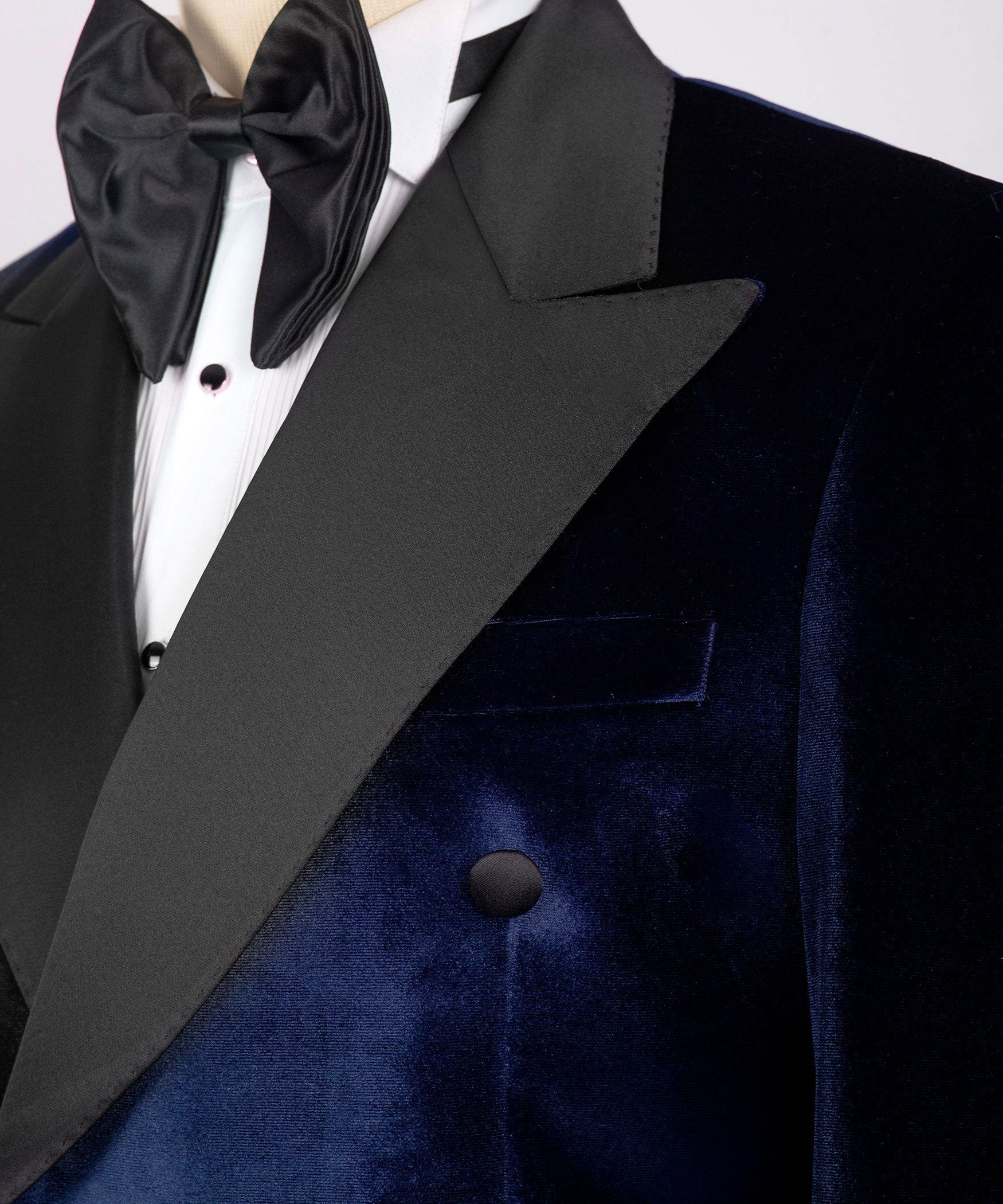 Close-up of black satin lapel, bow tie, and buttons on blue velvet tuxedo jacket