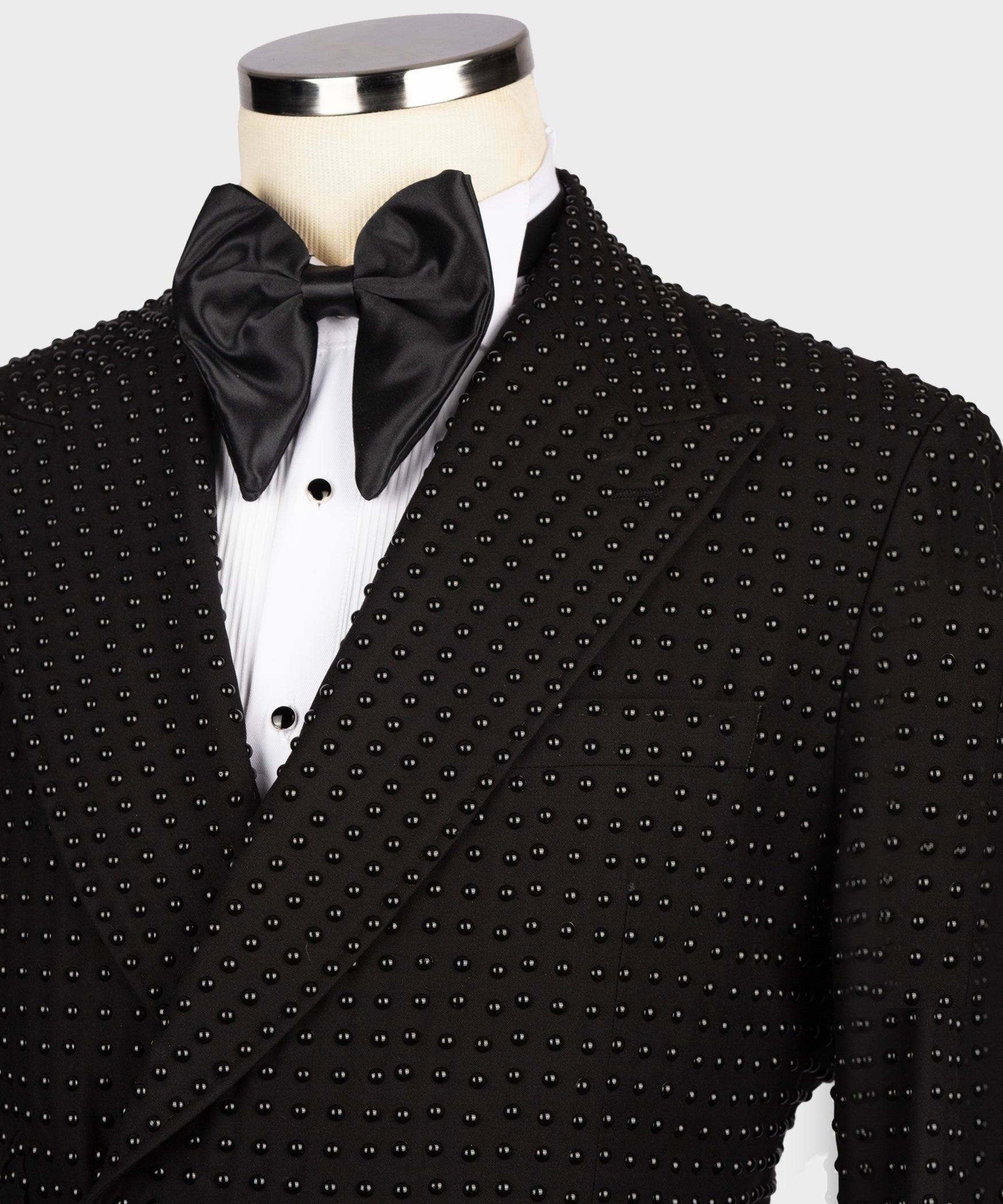Close-up of black tuxedo lapel with stone-studded embroidery and satin bow tie