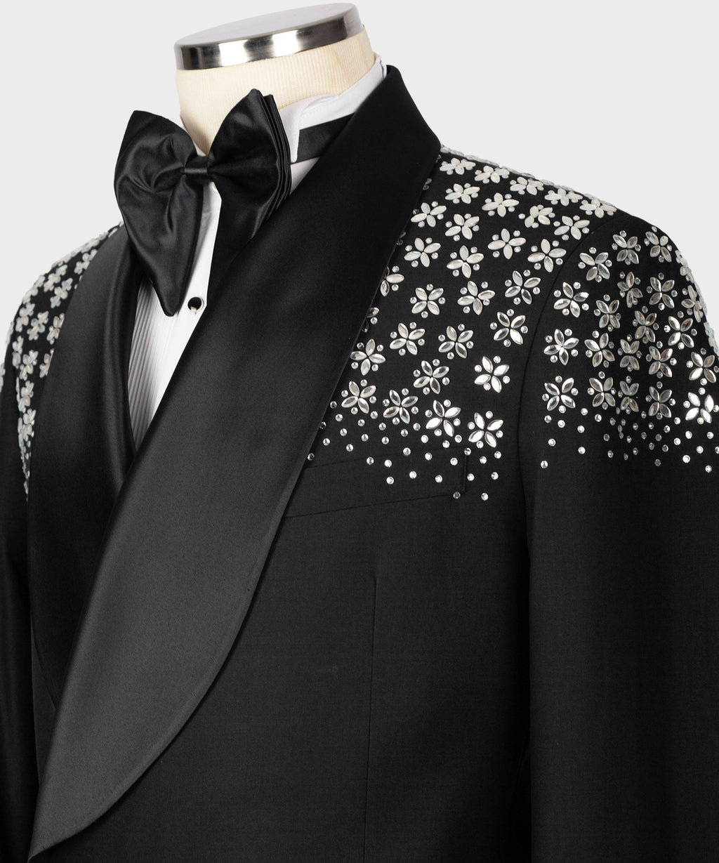 Black tuxedo jacket close-up: stone floral embroidery on sleeve and chest, satin lapel