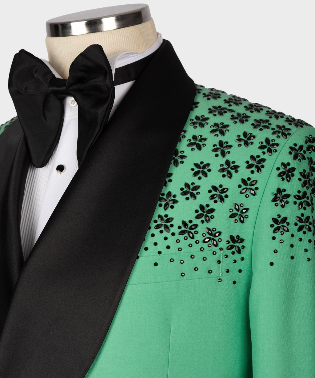 Black bow tie and white shirt under light green tuxedo jacket with stone floral embroidery.